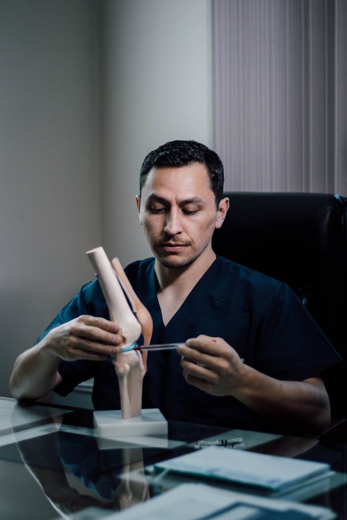 our-services-3 Professional doctor explaining knee anatomy with model in office setting, highlighting orthopedic expertise.